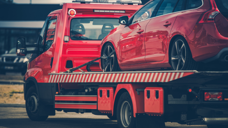 red tow truck carrying a red car